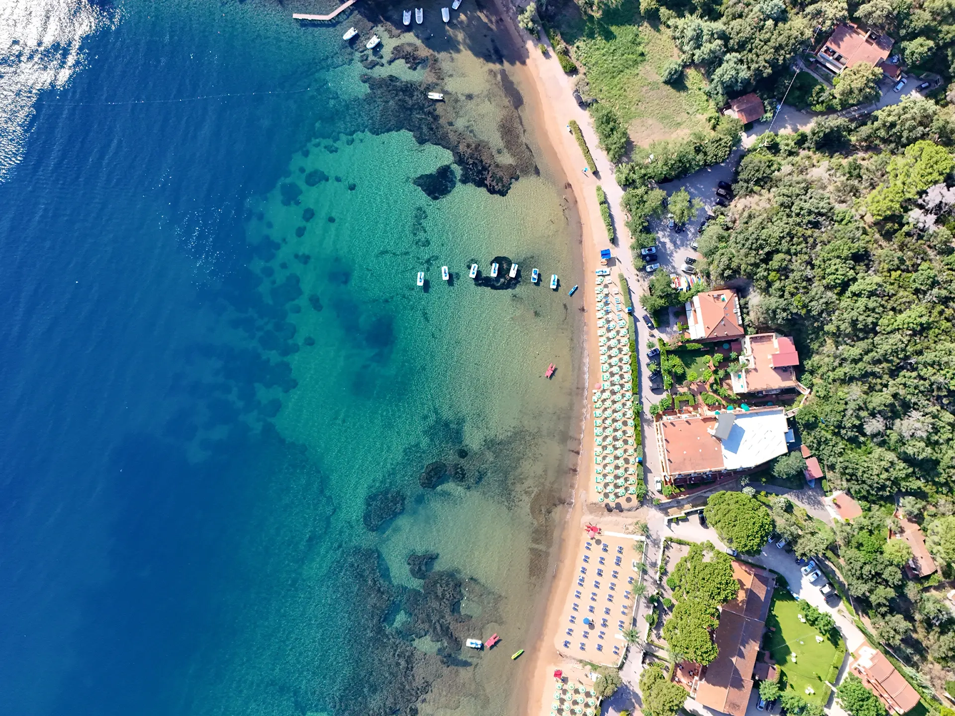 Vista aerea della costa dell'Isola d'Elba con spiaggia, barche ancorate e acqua turchese cristallina