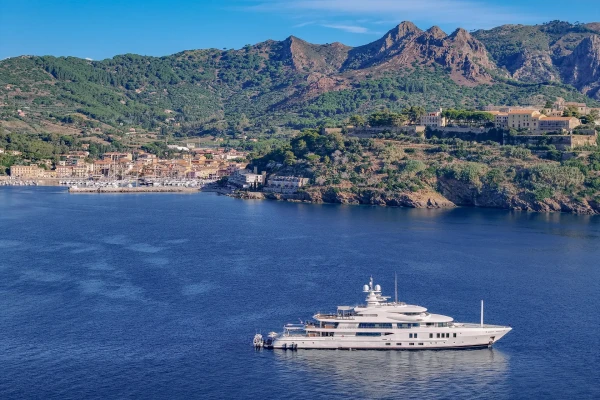 Yacht ancorato nella baia di Rio Marina con montagne e borgo sullo sfondo, Isola d'Elba