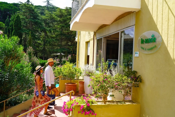 Terrazza fiorita dell'hotel all'Elba con ospiti tra piante e vista sulle colline verdi